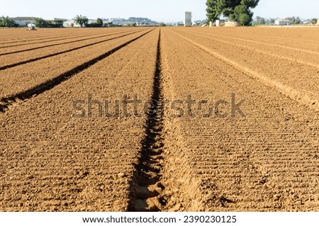 Agricultural Symmetry: Preparing the field with geometric furrows for planting. Royalty-Free Stock Photo #2390230125