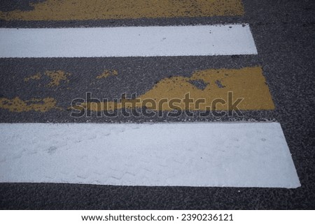 Pedestrian crossing. White and yellow stripes. Pedestrians and just people walk along the pedestrian crossing. Zebra Stripe