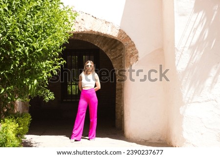 Young and beautiful brunette woman with blonde and latin hair is on holiday in seville. The woman is walking through the Jewish quarter of the Spanish city. The woman is enjoying the monuments