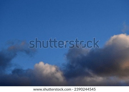 Crescent moon under colorful evening clouds