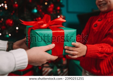 Gift box in the hands of mother and son, Christmas mood.