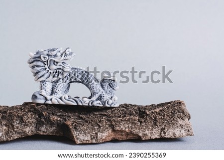 Ceramic dragon on tree bark on gray background for Chinese New Year