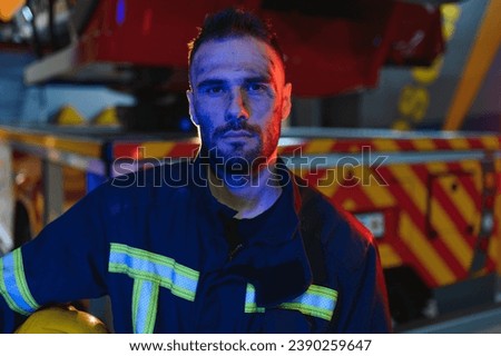 fireman in protective uniform standing near fire engine on station.