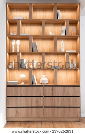 Vertical front shot of new wooden bookshelf with collections of magazines, books for reading stand on shelves at home library cabinet. Design of furniture with open space and drawers for living room
