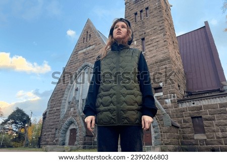 Portrait of young sad praying woman or religious teenager girl on Catholic Church background. 