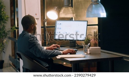 Bookkeeper in office making sure documents are compliant with quality assurance expectations and standards during nightshift. Employee checking paperwork details on computer screen Royalty-Free Stock Photo #2390279429