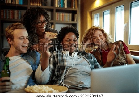 Young and diverse group of friends watching a movie on laptop in the living room on the couch