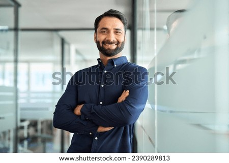 Happy Indian businessman professional leader standing arms crossed in office. Smiling male employee, business man company executive manager, confident eastern entrepreneur at work, portrait. Royalty-Free Stock Photo #2390289813