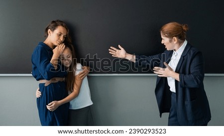 The teacher screams at the schoolgirl and her mother standing at the blackboard.  Royalty-Free Stock Photo #2390293523