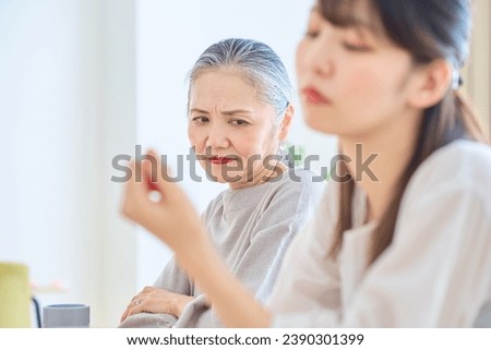 A senior woman looking at a young woman with a grim expression Royalty-Free Stock Photo #2390301399