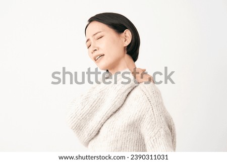 Asian middle aged woman having stiff shoulders in white background Royalty-Free Stock Photo #2390311031