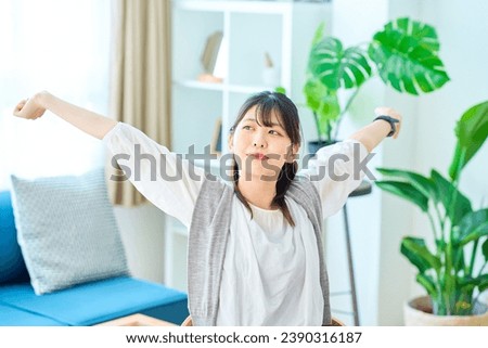 A young woman taking a deep breath in a casual space Royalty-Free Stock Photo #2390316187