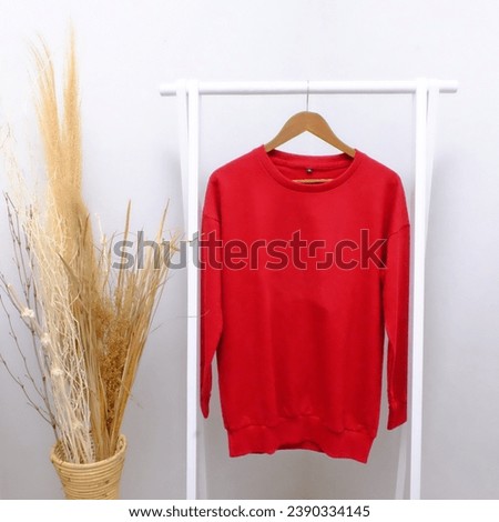 Countryside Chic: Mockup of Long Sleeve Plain Red Sweaters on a Hanger, Enhanced with Hay and Ornamental Grasses. Effortless Comfort Meets Rural Charm.