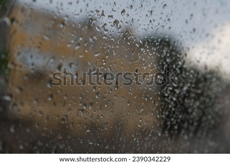 Abstract rainy background. Few raindrops on car or turboat window. Dark blurred city buildings in the background. Soft focus. Copy space for your text. Bad weather forecast theme.