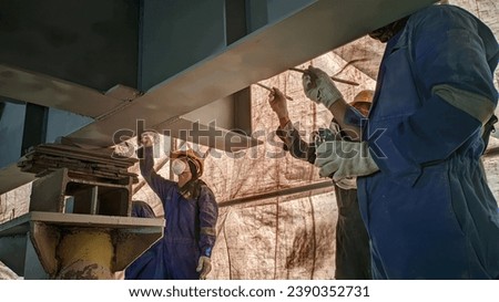 Several workers paint steel on a project