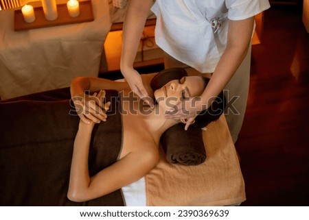 Caucasian woman enjoying relaxing anti-stress head massage and pampering facial beauty skin recreation leisure in warm candle lighting ambient salon spa in luxury resort or hotel. Quiescent Royalty-Free Stock Photo #2390369639