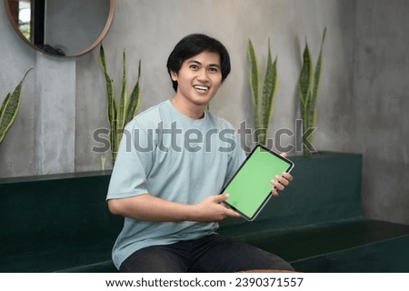 Potrait of Young Asian men holding a tablet PC in a cafe workplace with expressive faces