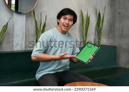 Potrait of Young Asian men holding a tablet PC in a cafe workplace with expressive faces