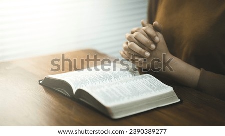 Christian woman hold hands read the Bible, worship, and pray to God at the table in church on Sunday mornings. Hand person prayer and confession at home