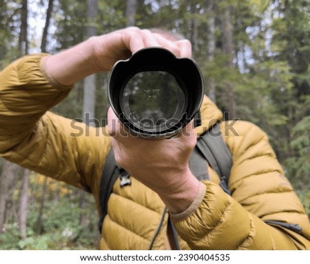 Photographer taking photo in nature, holding digital camera