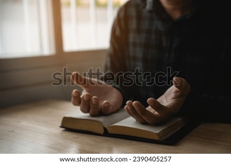 Close up of hand. Man doing hands together in prayer to God along with the bible In the Christian concept of faith, spirituality and religion, men pray in the Bible. prayer bible at home.