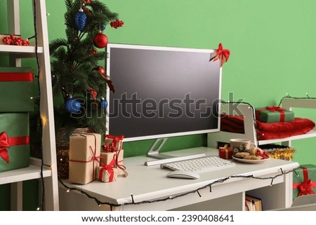 Blank computer monitor with Christmas presents on table in office