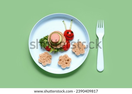 Plate with funny children's breakfast in shape of snail on green background