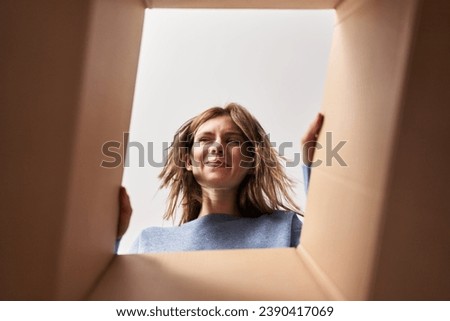 Beautiful woman opening cardboard box smiling looking to the side and staring away thinking. 