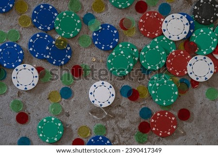 View of blue, green, red and white casino game chips on a concrete floor