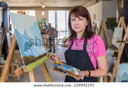 Young woman painting mountains in art studio