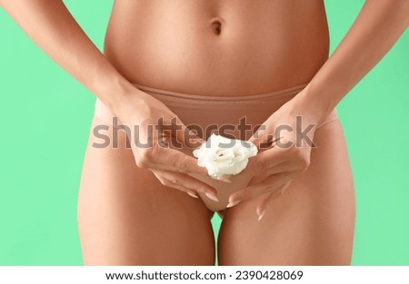 Young woman in underwear and with flower on green background, closeup. Gynecology concept