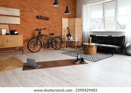 Interior of living room with sports equipment, bicycle and laptop