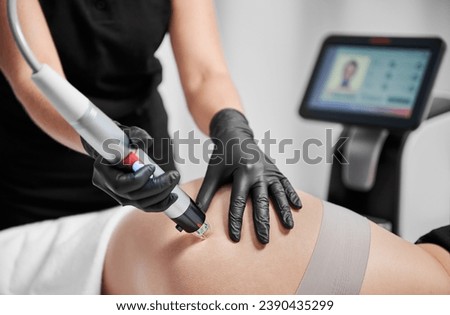 Close up of cosmetologist using radiofrequency microneedling device while removing stretch marks on female skin. Woman having skin tightening procedure in beauty salon. Hardware cosmetology concept. Royalty-Free Stock Photo #2390435299