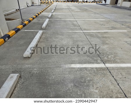 Empty parking stalls in a concrete parking lot or parking space with marked with white lines and car stopper yellow 