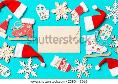 Top view of craft envelope with Christmas decorations and Santa hats on blue background. Happy holiday concept.