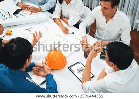 Diverse group of civil engineer and client working together on architectural project, reviewing construction plan and building blueprint using tablet at meeting table. Prudent Royalty-Free Stock Photo #2390444551