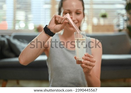 Sporty woman dissolving collagen powder in a glass of water. Dietary supplement, healthcare concept