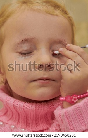 little girl draws eyebrows,the girl plays with cosmetics, drawing eyebrows with closed eyes