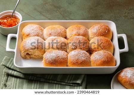 Homemade sweet bread rolls, buns powdered with sugar and filled with apricot jam, in a cooking tray. Royalty-Free Stock Photo #2390464819