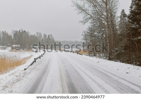 Winter landscape view of plowed road in cloudy winter weather, Pellinki, Finland. Royalty-Free Stock Photo #2390464977