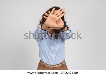 Scared sad young european lady making stop sign with hand, close face with hands, isolated on gray background studio background. Problems with work, fight with sexism, harassment, violence