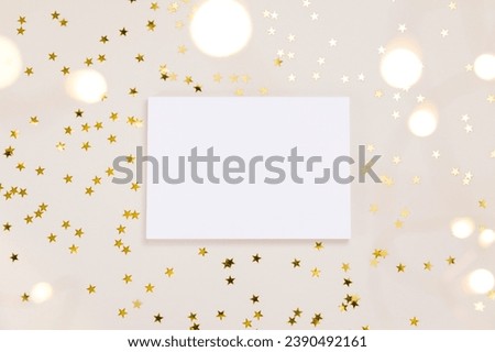 Festive gold background. Empty paper blank, shining stars confetti and fairy lights on beige and Set Sail Shampagne background. Christmas. Wedding. Birthday. Flat lay, top view, copy space.