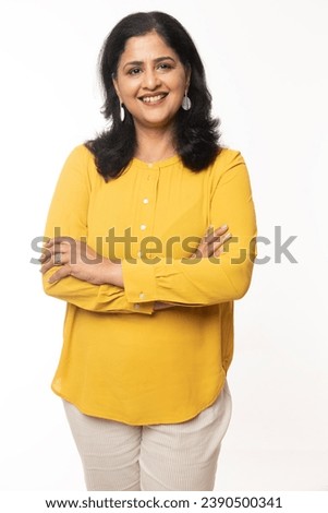 Portrait of beautiful happy woman looking at camera wearing casual yellow dress on white. female arms crossed Royalty-Free Stock Photo #2390500341