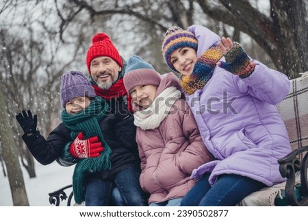 Portrait of full friendly family sitting bench chilling arm waving hi snowfall weather outside