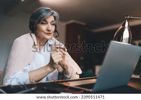 Happy mature woman using laptop in living room