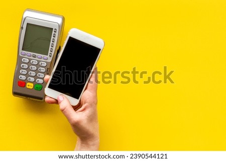 Payment by mobile phone pay. Female hand with mobile phone near POS payment terminal.