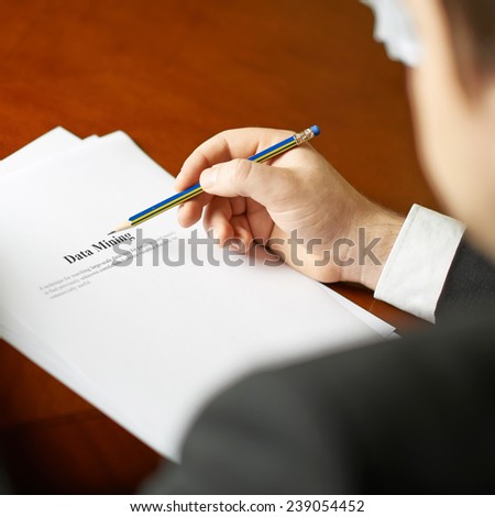 Data mining definition as a shallow depth of field close-up composition of a man in a business suit working with the text