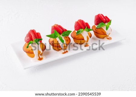 Vanilla cupcakes with strawberry on white plate