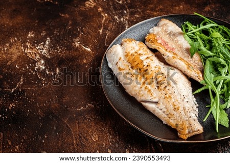 Roasted Snapper, sea red perch fillet on a plate with salad. Dark background. Top view. Copy space. Royalty-Free Stock Photo #2390553493