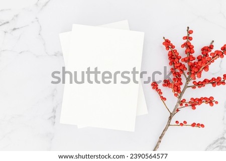 Empty blank white magazine cover mock up and branch with red berries on white marble table background. Christmas, New Year, winter concept. Flat lay, top view, copy space. 